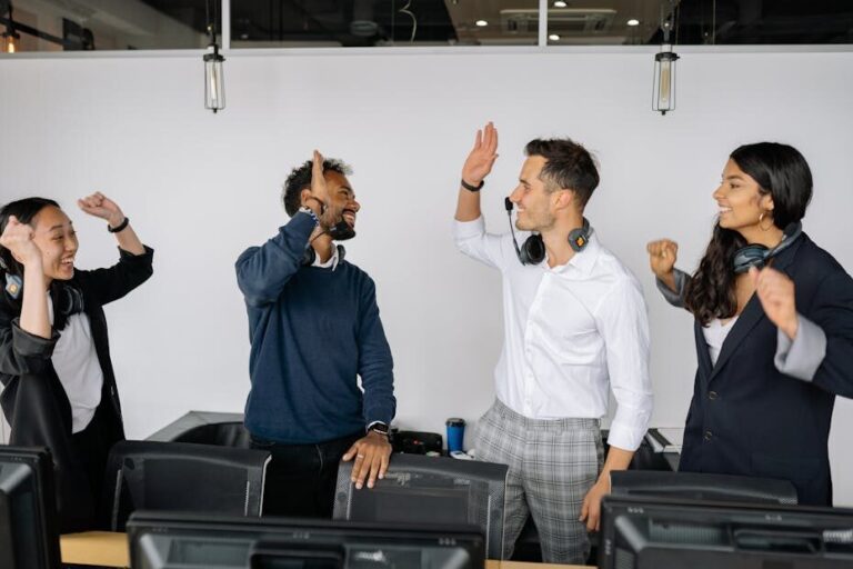 A diverse group of coworkers high-fiving in a modern office, showcasing teamwork and success.